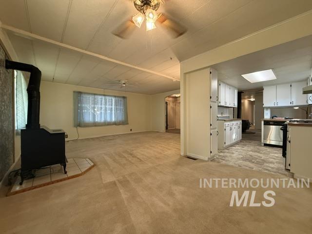 1360 Pioneer Road Weiser, ID 83672 - Photo 7 of 47 Living area featuring a wood-burning stove with a tile hearth and beige carpeting