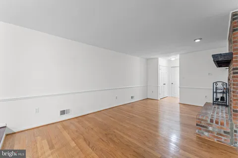 an empty room with wooden floor chandelier fan and windows