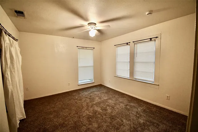 an empty room with windows and fan