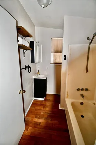 a bathroom with a tub a sink and wooden floor