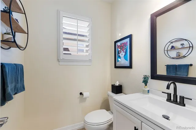 a bathroom with a toilet sink vanity and mirror