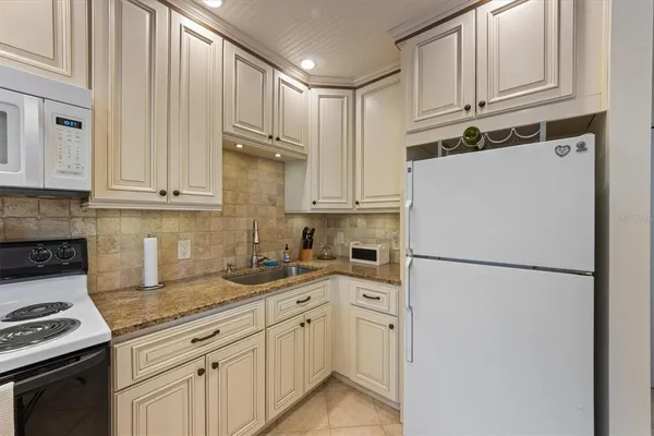 a kitchen with stainless steel appliances granite countertop a refrigerator sink stove and cabinets