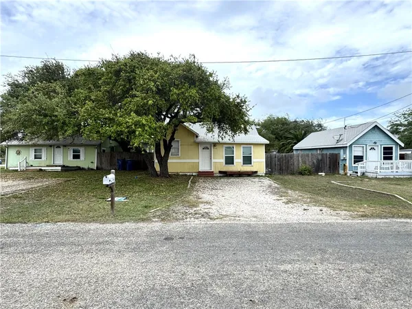 a front view of a house with a yard and a large tree