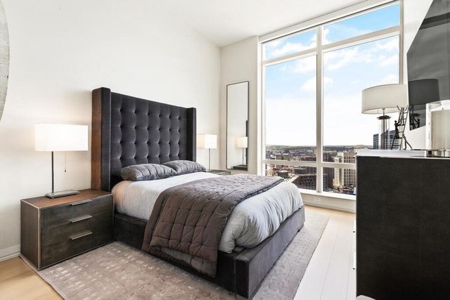 a bedroom with a bed lamp and a large window