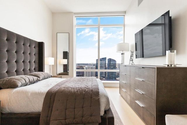 a bedroom with a large bed and a flat tv screen on dresser