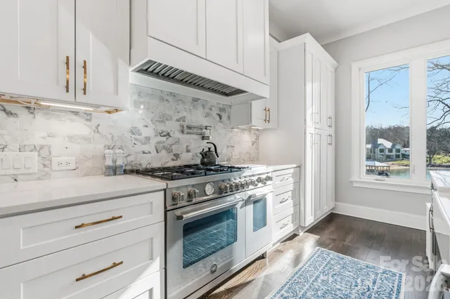 a kitchen with stainless steel appliances granite countertop a stove and a white cabinet