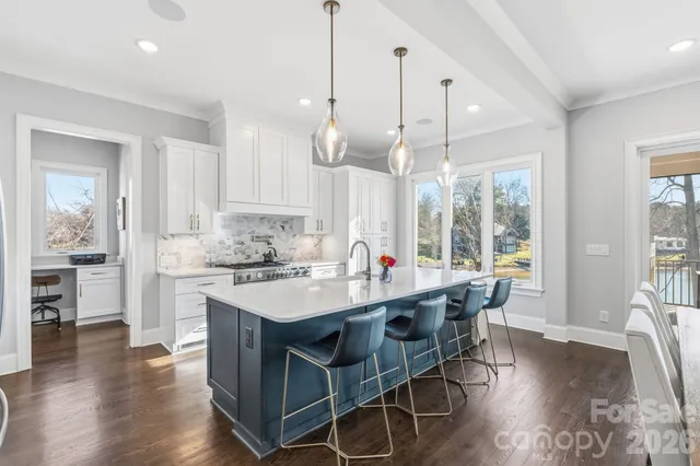 a kitchen with stainless steel appliances a dining table chairs a sink and dishwasher a refrigerator with wooden floor