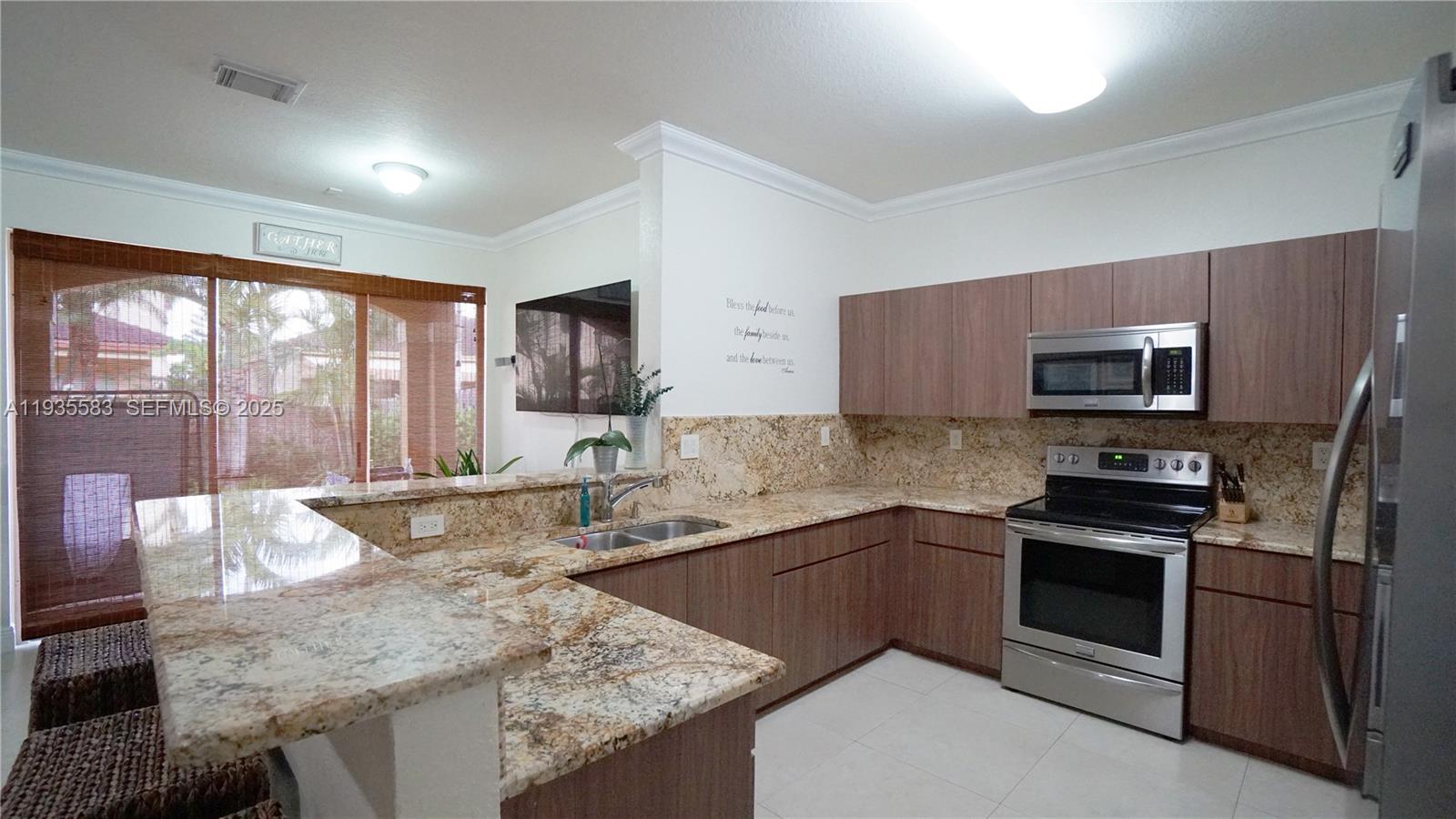 928 Southwest 154th Path, Unit 928 Miami, FL 33194 - Photo 11 of 39 a kitchen with stainless steel appliances granite countertop a sink stove microwave and refrigerator