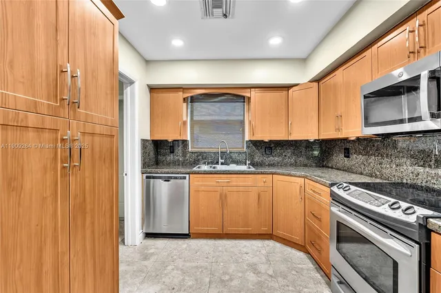 a kitchen with stainless steel appliances granite countertop a stove a sink and a microwave