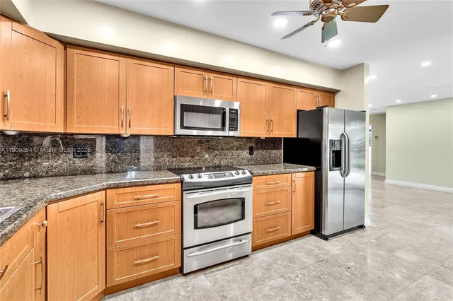 a kitchen with stainless steel appliances granite countertop a stove a sink and a refrigerator