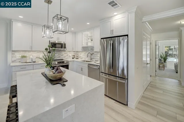 a kitchen with stainless steel appliances a sink a stove a refrigerator and cabinets