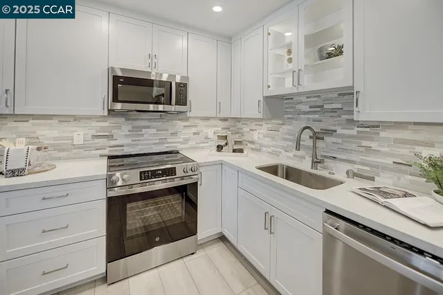 a kitchen with white cabinets stainless steel appliances and sink