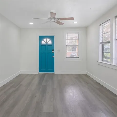a view of an empty room with wooden floor and windows