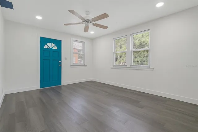 a view of an empty room with a window and wooden floor