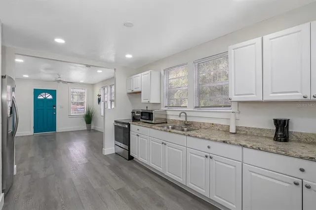 a kitchen with granite countertop cabinets stainless steel appliances a sink and a window