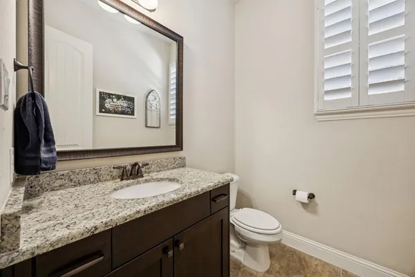 a bathroom with a granite countertop sink toilet and mirror