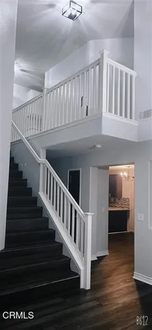 a view of an empty room with wooden floor and a kitchen