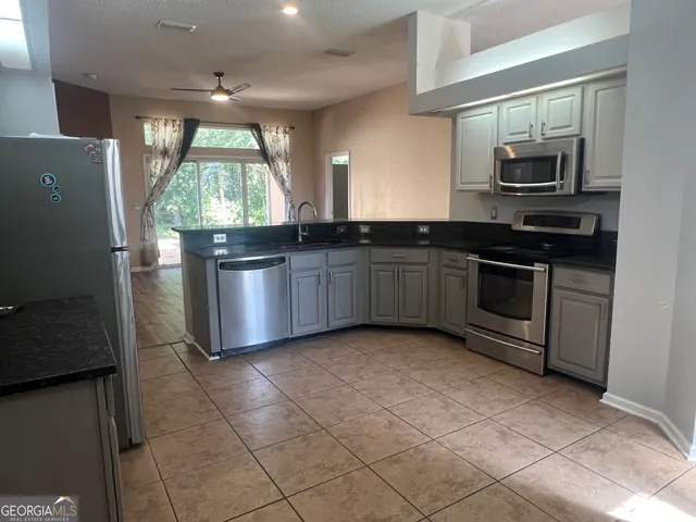 a kitchen with stainless steel appliances granite countertop a stove a sink and a microwave