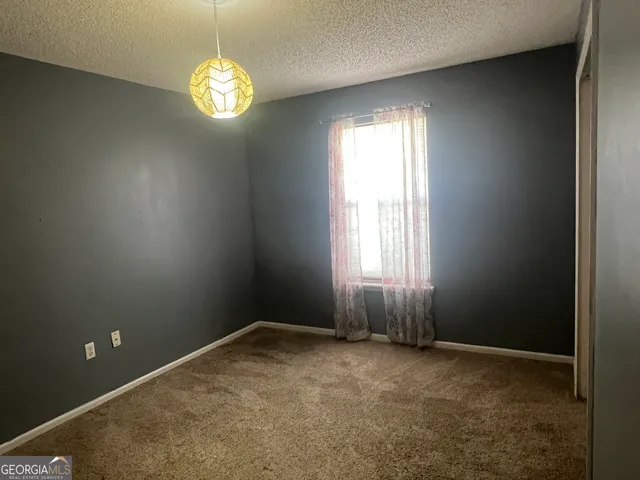 an empty room with windows and chandelier fan