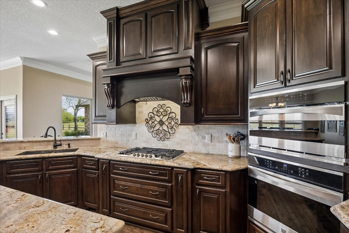 17703 Cedarhill Drive Rosharon, TX 77583 - Photo 13 of 47 Every detail impresses — a dramatic custom wood hood, gas cooktop, stone backsplash, deep granite counters, and a stainless wall oven with built-in microwave deliver a professional-grade cooking experience within a stunningly crafted space.