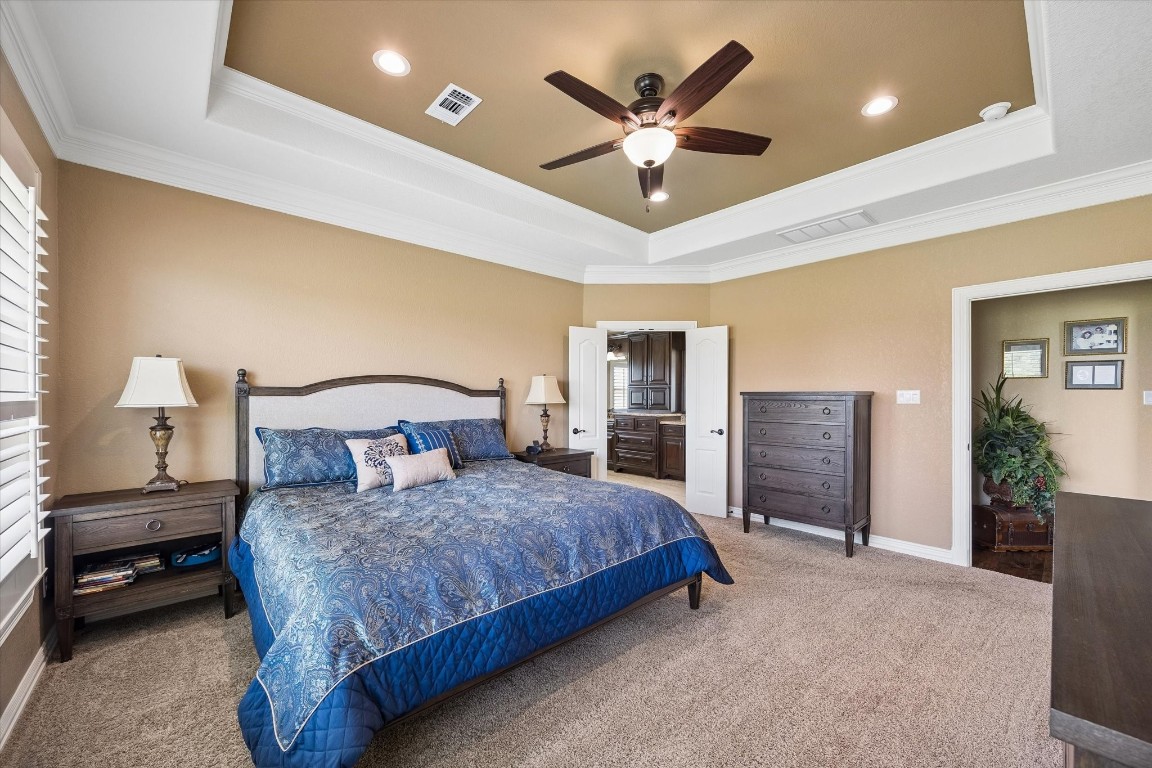 17703 Cedarhill Drive Rosharon, TX 77583 - Photo 16 of 47 Generous in scale and refined in detail, the primary bedroom showcases a coffered tray ceiling, crown molding, recessed lighting, and a serene neutral palette — a quiet sanctuary at the end of every day.