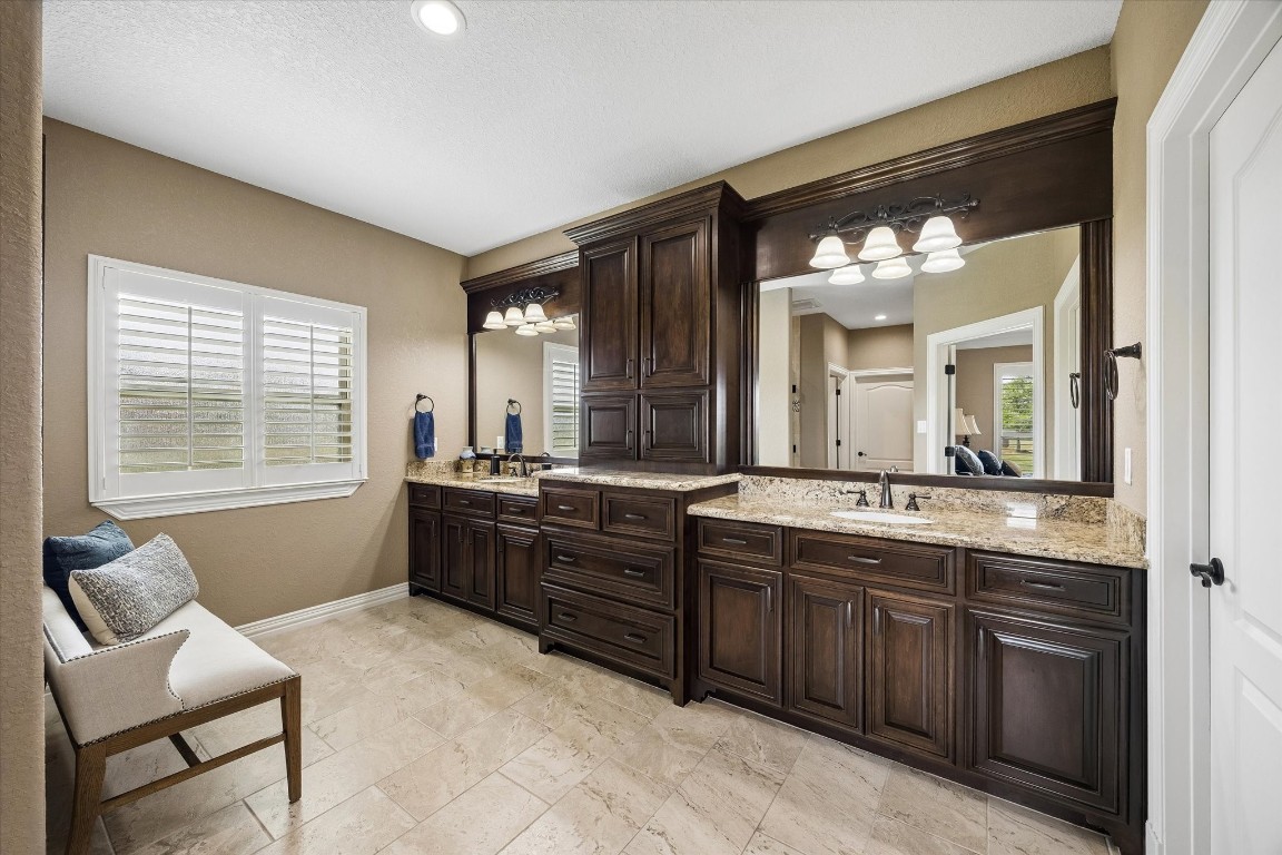 17703 Cedarhill Drive Rosharon, TX 77583 - Photo 17 of 47 The spa-inspired primary bath impresses with an expansive dual vanity featuring custom dark cabinetry, granite countertops, framed mirrors, and a built-in linen tower — offering his-and-hers storage and a luxurious start to every day.