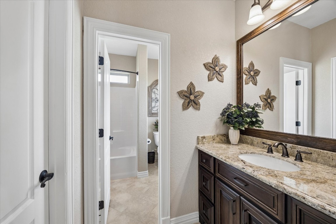 17703 Cedarhill Drive Rosharon, TX 77583 - Photo 20 of 47 A beautifully appointed Jack-and-Jill bath connecting both secondary bedrooms, featuring granite countertops, dark custom cabinetry, oil-rubbed bronze fixtures, and a separate wet room with tub and shower.