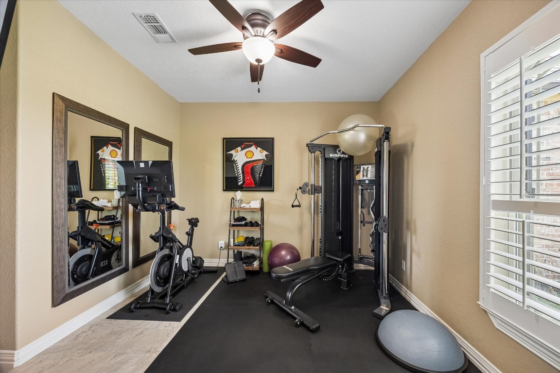 17703 Cedarhill Drive Rosharon, TX 77583 - Photo 22 of 47 Tucked in a separate, private wing of the home, this versatile 4th bedroom adapts effortlessly to your lifestyle — currently serving as a home gym with plantation shutters and ceiling fan, but equally suited as a guest suite, hobby space, or second home office. A dedicated full bath with walk-in shower makes this wing ideal for multigenerational living or long-term guests seeking their own private retreat.