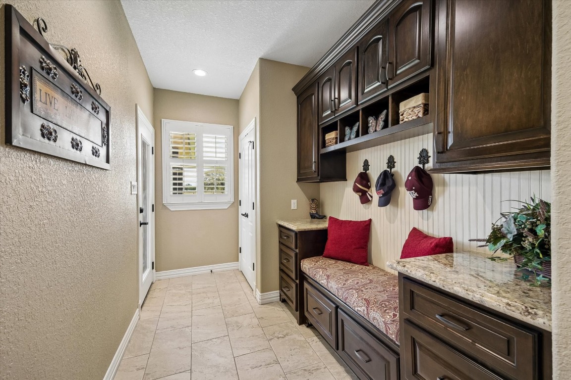 17703 Cedarhill Drive Rosharon, TX 77583 - Photo 29 of 47 A beautifully designed mudroom features custom dark cabinetry, open cubbies, decorative hooks, a built-in bench with storage drawers, granite countertops, and plantation shutters — the perfect drop zone that keeps everyday life organized and stylish.