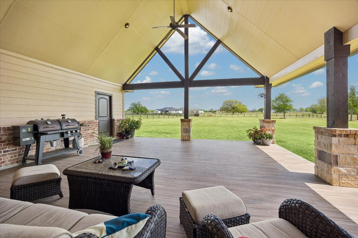 17703 Cedarhill Drive Rosharon, TX 77583 - Photo 32 of 47 Designed for Texas-sized entertaining, this expansive covered patio offers generous seating space, wood-look tile floors, a dedicated grilling area, and stunning open views of the lush backyard and fenced acreage beyond — perfect for gatherings year-round.