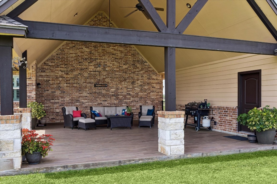 17703 Cedarhill Drive Rosharon, TX 77583 - Photo 33 of 47 Viewed from the yard, the grandeur of this vaulted covered patio is undeniable — cathedral beam ceilings, stone columns, wood-look tile decking, and a full outdoor living and grilling setup make this backyard a true destination for family and friends.