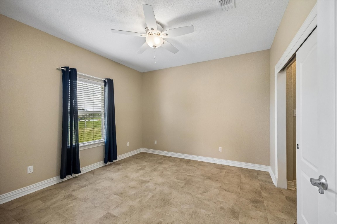 17703 Cedarhill Drive Rosharon, TX 77583 - Photo 36 of 47 The casita bedroom offers a generous, light-filled space with ceiling fan, tile flooring, and a walk-in closet — comfortable and private, ideal for extended family, long-term guests, or a live-in caregiver suite.