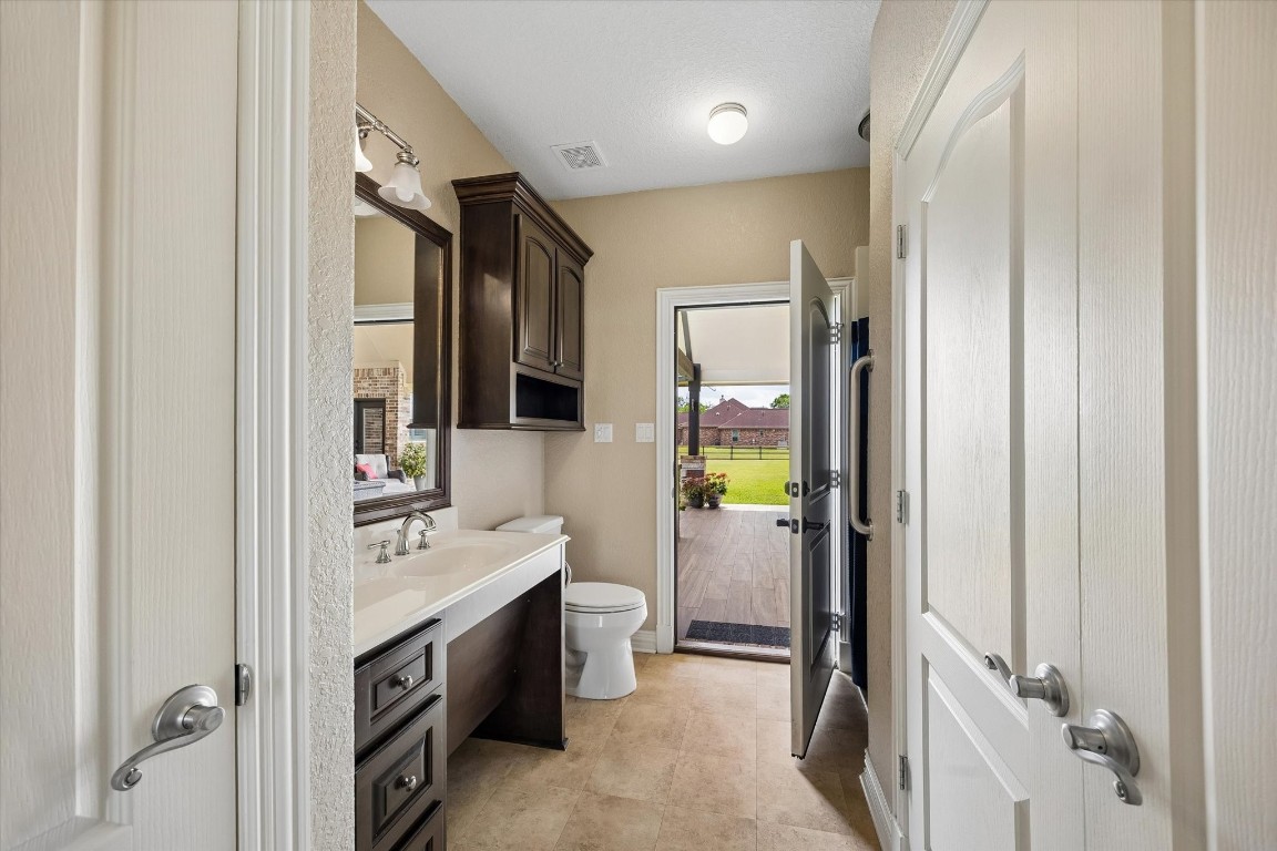17703 Cedarhill Drive Rosharon, TX 77583 - Photo 37 of 47 The casita's full bathroom is thoughtfully designed with custom dark cabinetry, a vanity with granite countertops, framed mirror, and a walk-in shower — with a door opening directly to the covered patio, seamlessly connecting indoor and outdoor living.