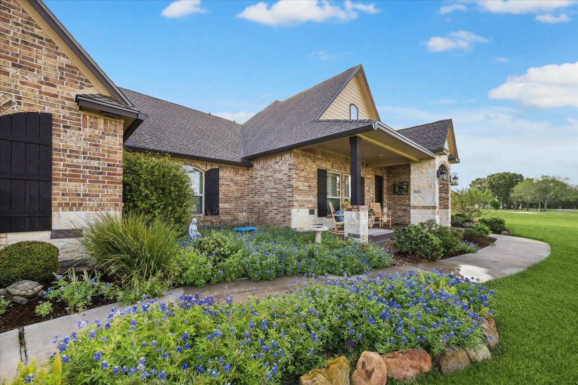 17703 Cedarhill Drive Rosharon, TX 77583 - Photo 4 of 47 A charming covered front porch with lantern lighting invites you to sit and stay a while, surrounded by vibrant Texas bluebonnets, native landscaping, and manicured gardens — a true Hill Country-inspired welcome.