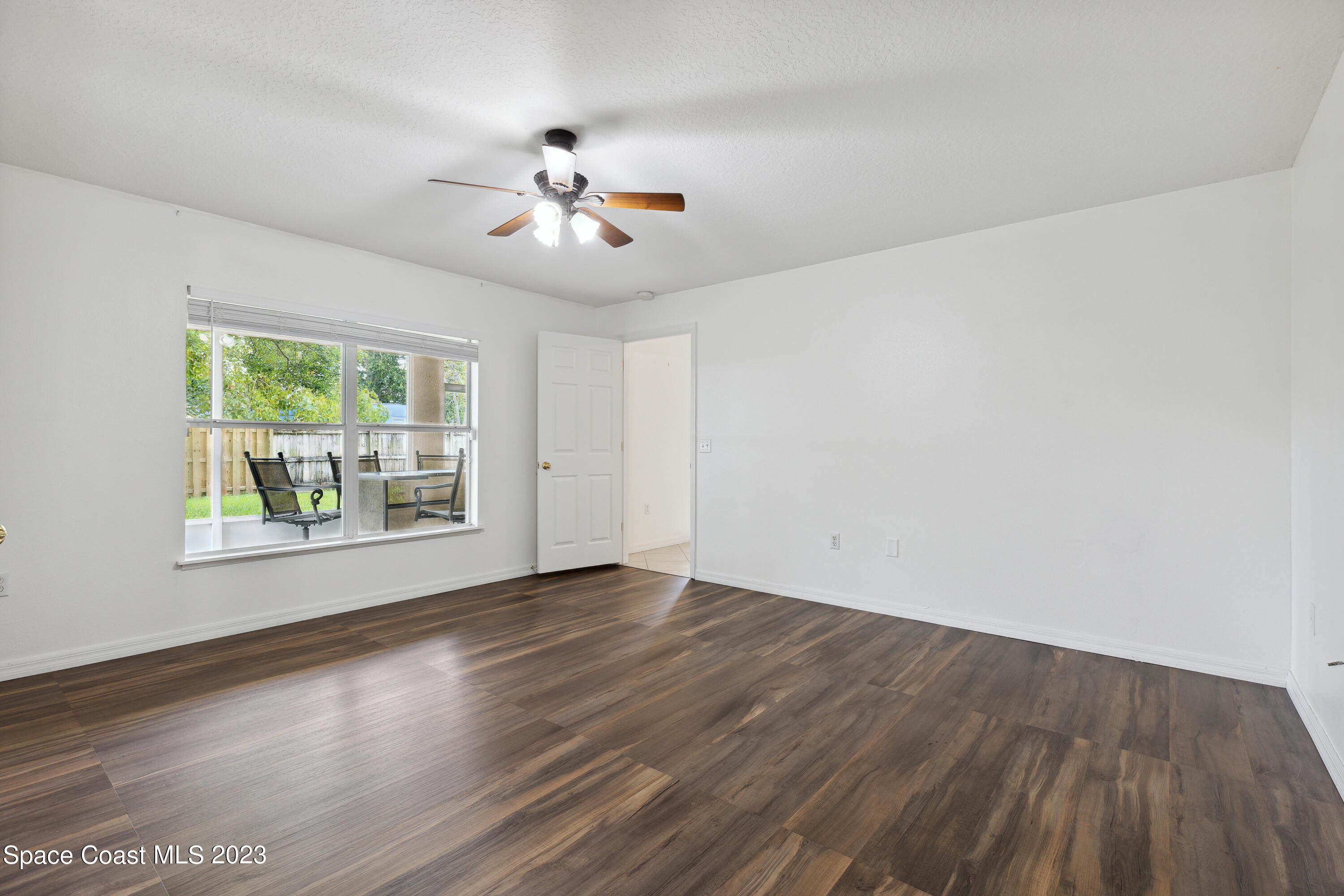 4625 Elena Way Melbourne, FL 32934 - Photo 11 of 26 a view of an empty room with wooden floor and a window