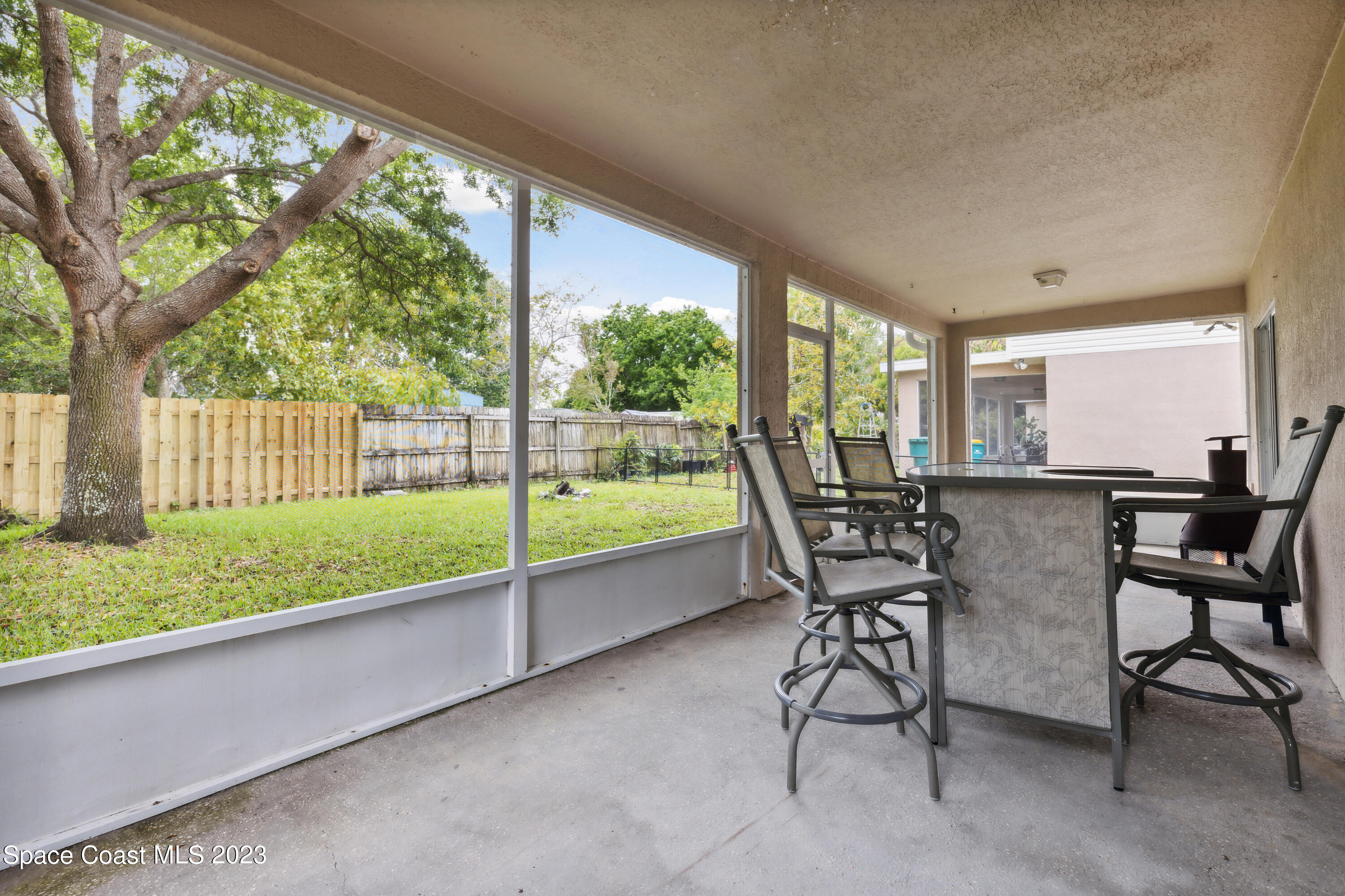4625 Elena Way Melbourne, FL 32934 - Photo 22 of 26 a view of a patio with table and chairs floor to ceiling window and a small yard
