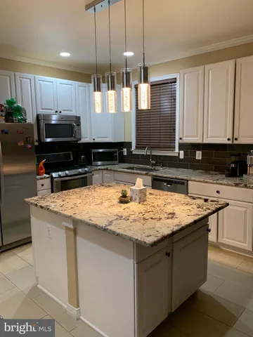 a kitchen with kitchen island granite countertop a sink a counter top space a stove and cabinets
