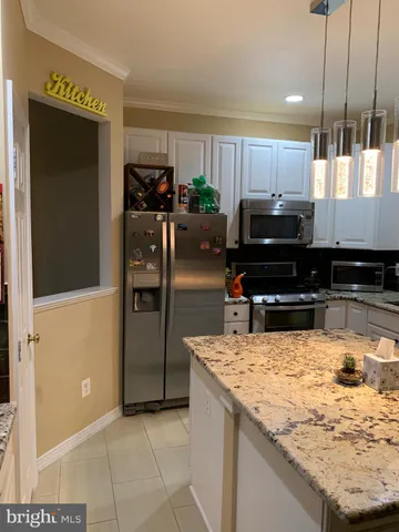 a kitchen with kitchen island granite countertop a refrigerator and a sink