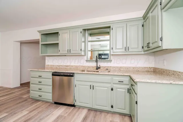 a kitchen with granite countertop a sink stainless steel appliances and cabinets