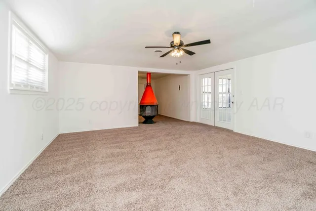 an empty room with windows and ceiling fan