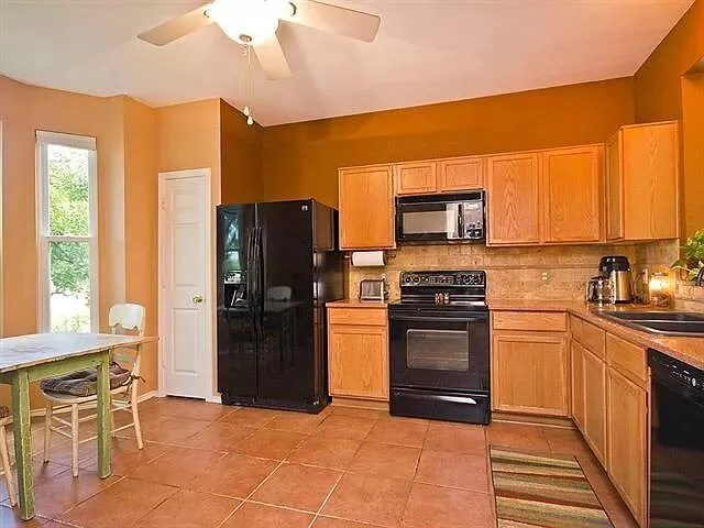 a kitchen with granite countertop a refrigerator stove top oven and sink
