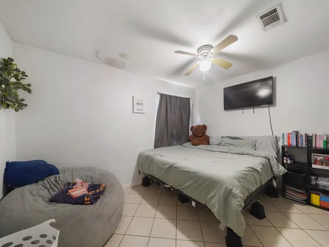a bedroom with a bed and a flat tv screen on the dresser
