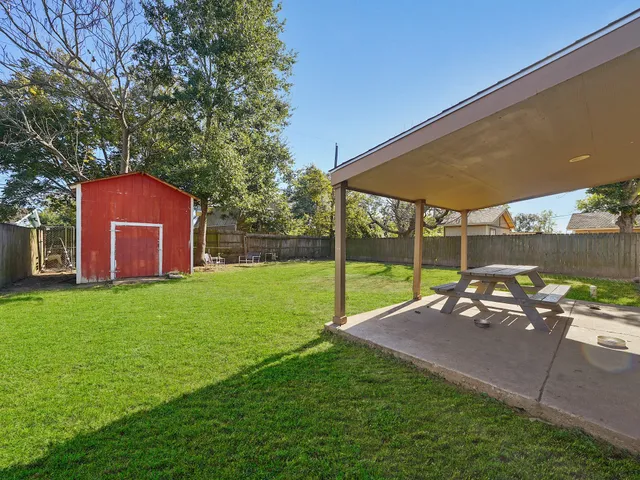 a view of a backyard with table and chairs under an umbrella