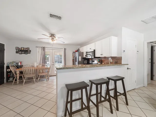 a kitchen with stainless steel appliances granite countertop a table and chairs in it