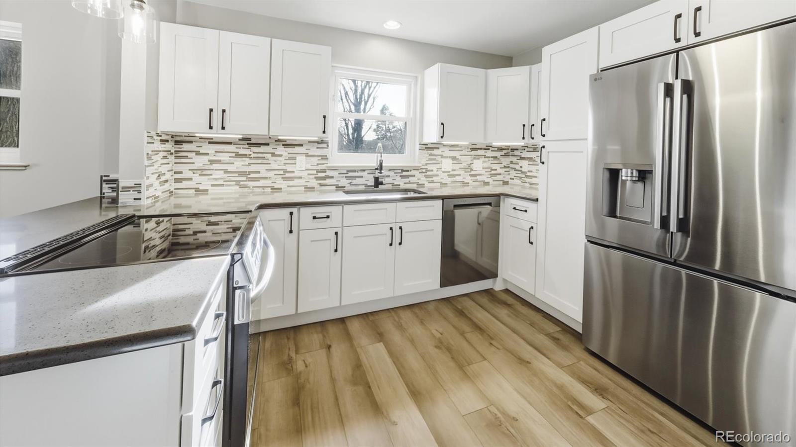 1201 Reed Street Lakewood, CO 80214 - Photo 12 of 44 a kitchen with stainless steel appliances granite countertop a refrigerator sink and white cabinets