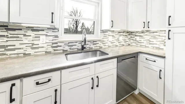 a kitchen with granite countertop a sink and white cabinets