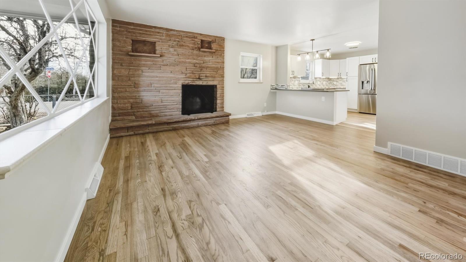 1201 Reed Street Lakewood, CO 80214 - Photo 6 of 44 a open kitchen with kitchen island wooden floors granite counter tops and a fireplace