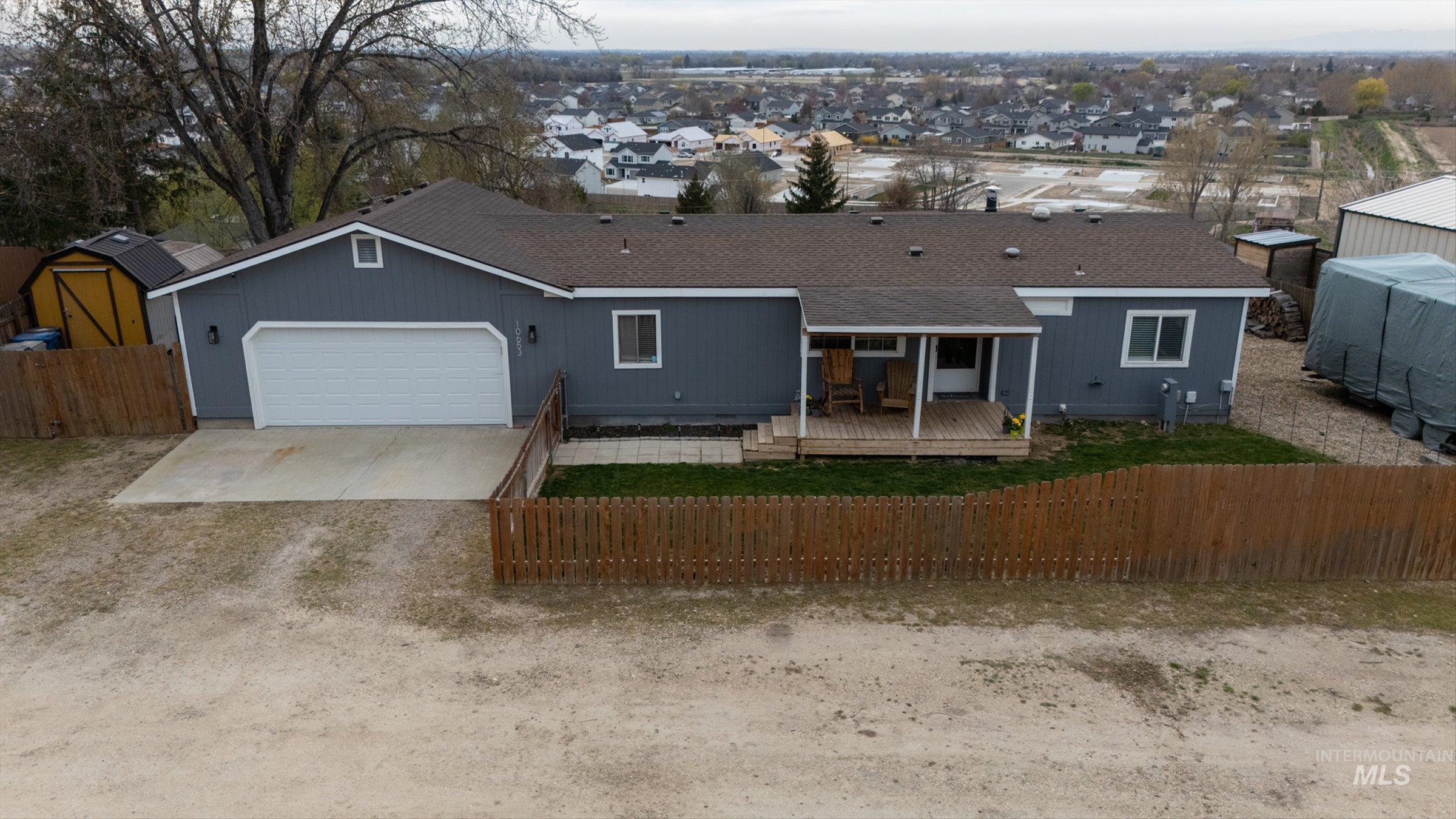 Ranch-style home with a deck, concrete driveway, a garage, a residential view, and roof with shingles