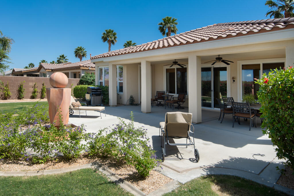 a view of a patio with table and chairs potted plants and floor to ceiling window