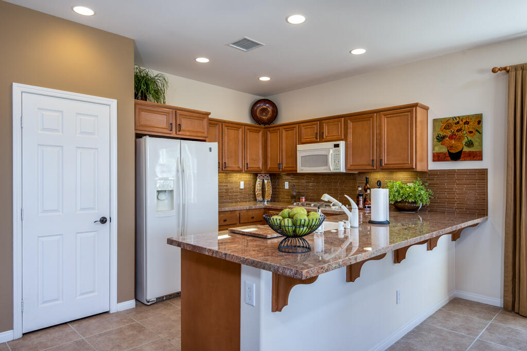 81820 Eagle Claw Drive La Quinta, CA 92253 - Photo 7 of 36 a kitchen with stainless steel appliances kitchen island granite countertop a refrigerator and a sink